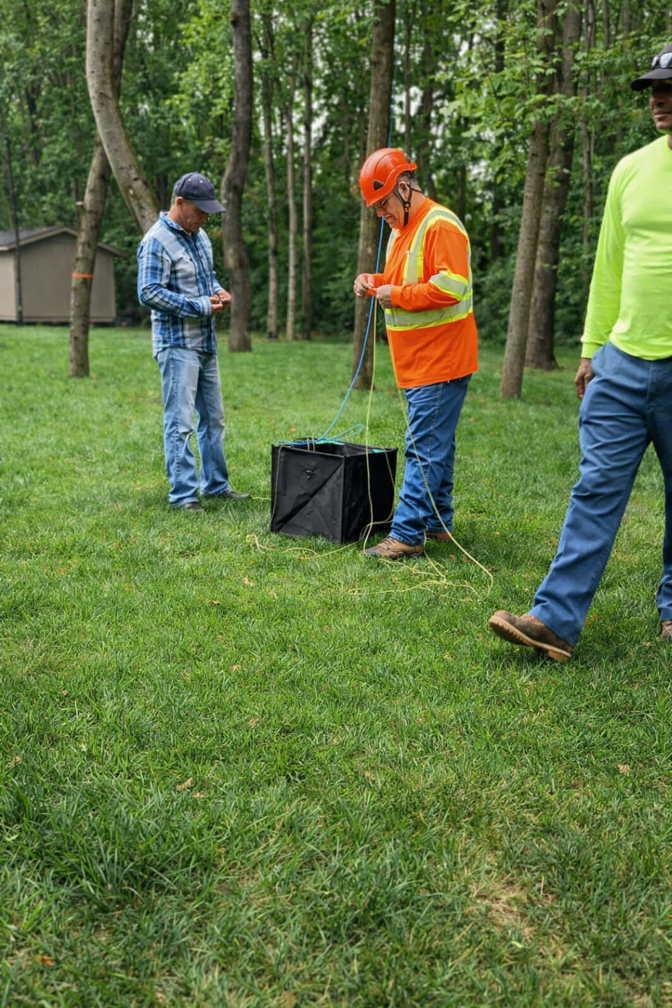 Crew members preparing ropes and rigging on a grassy work site