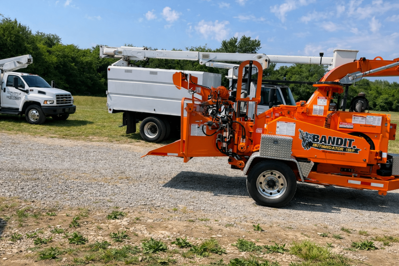Close view of orange Bandit chipper with bucket truck behind it