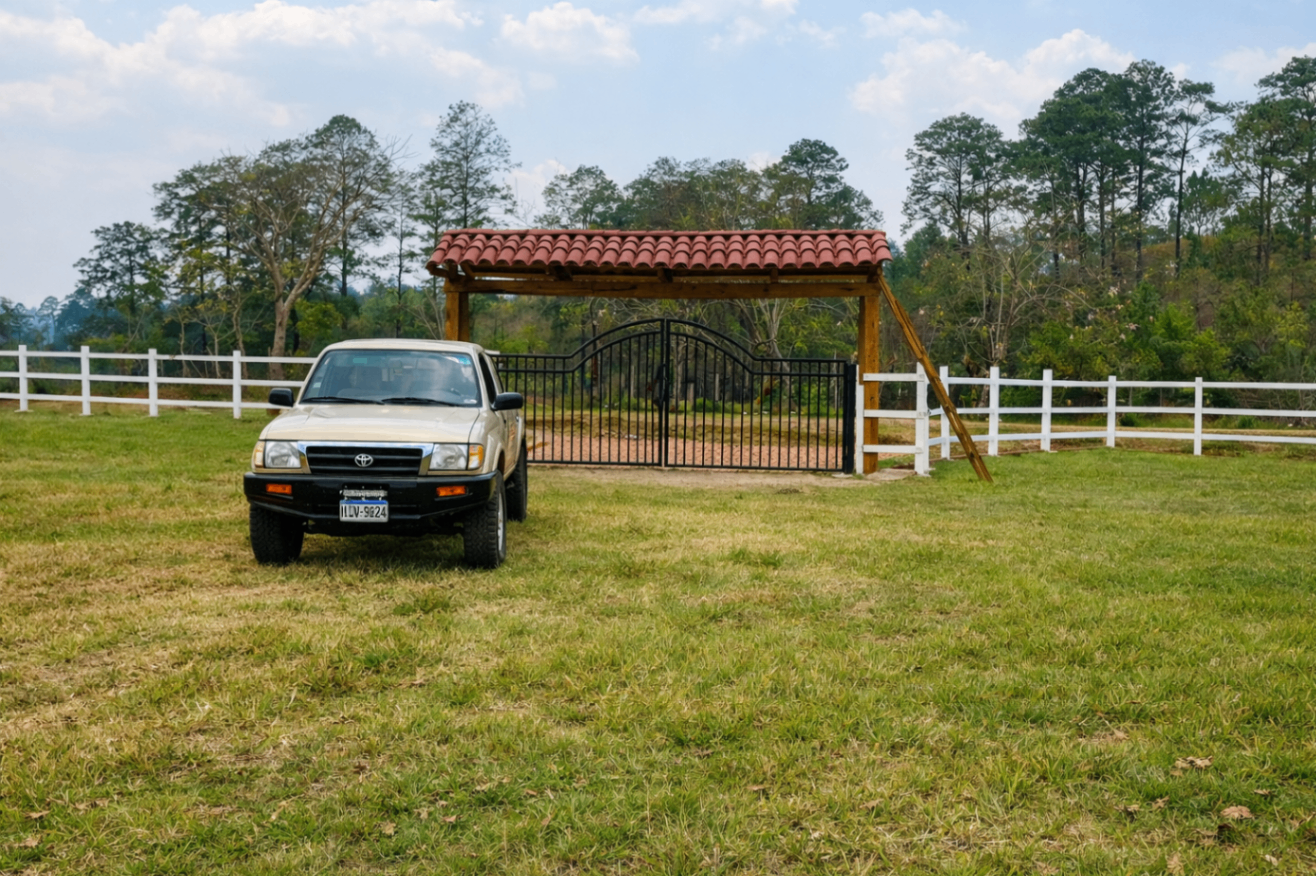 Vehicle parked near a ranch-style entry gate and fencing