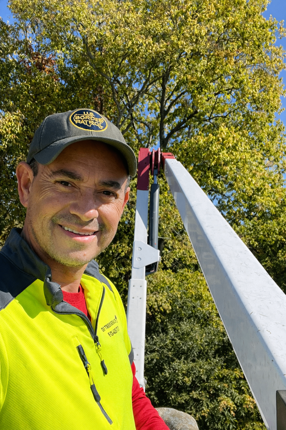 Portrait of a team leader smiling from an elevated bucket beside the trees