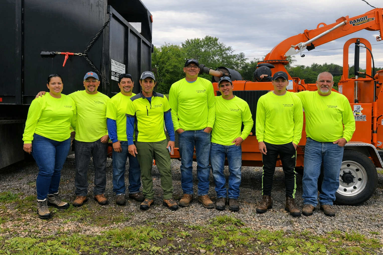 Full DJ Tree Service crew posing together in front of the chip truck and equipment