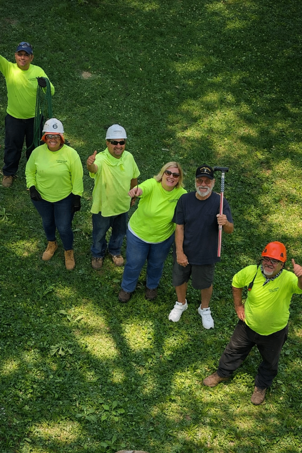 Team members and clients looking up and smiling from the grass below