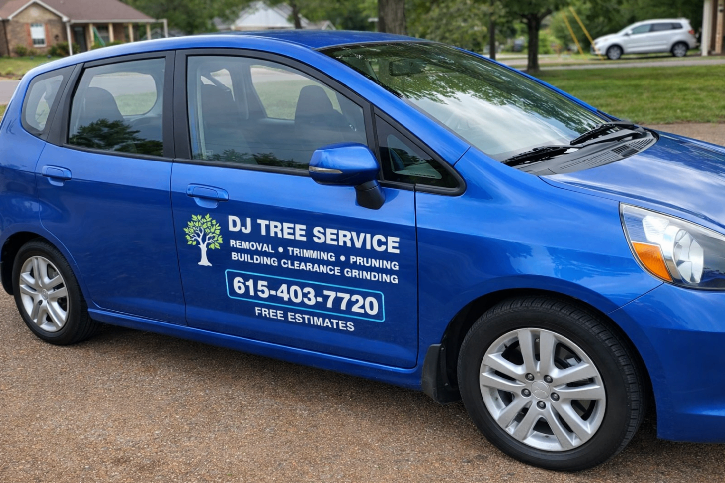 Blue compact car branded with DJ Tree Service graphics