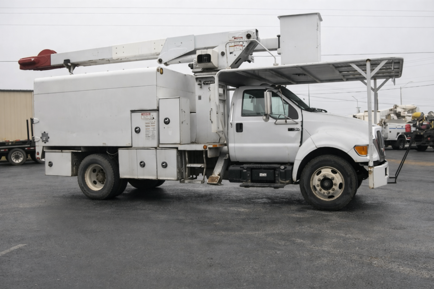 Side profile of a white bucket truck parked on asphalt